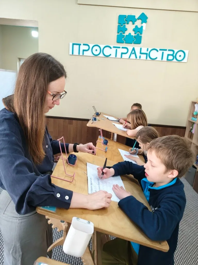 Ученики работают за конторками с наставником
