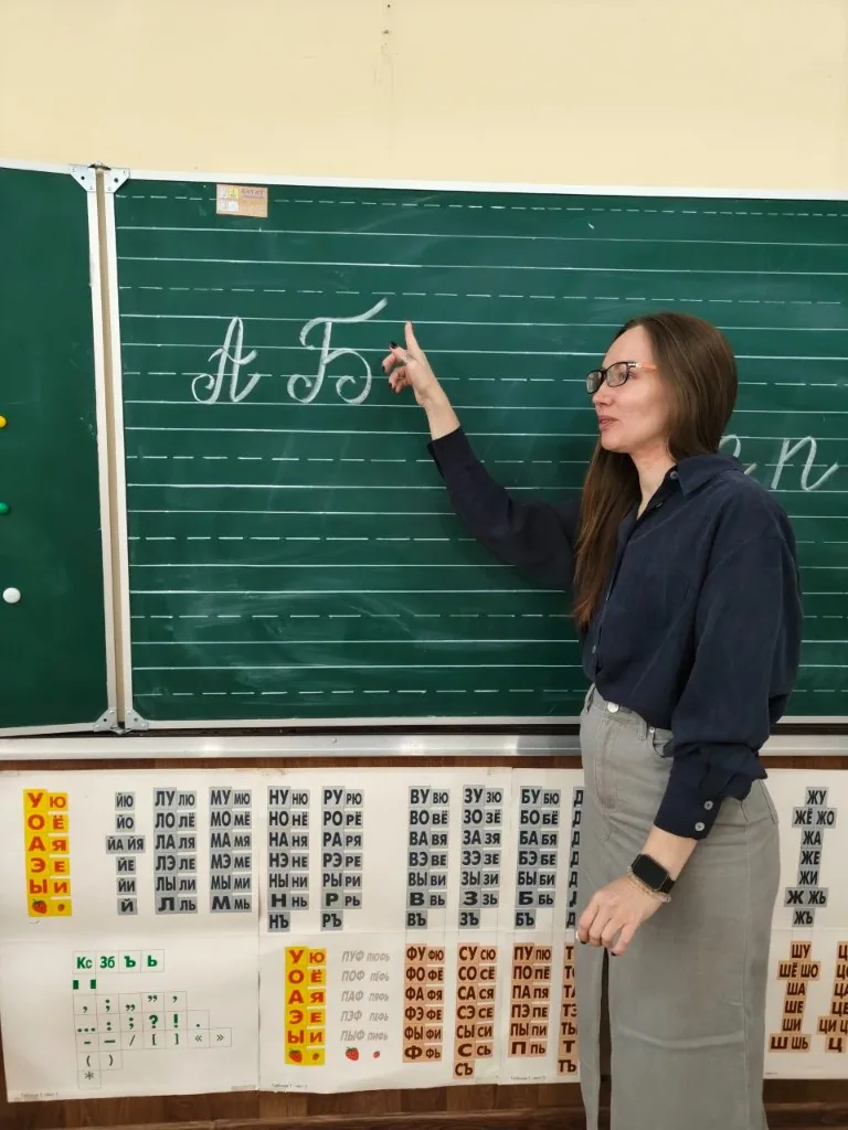 Наставник показывает написание букв на доске